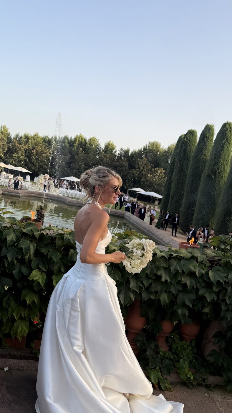 Bride with bouquet beside the fountain at golden hour